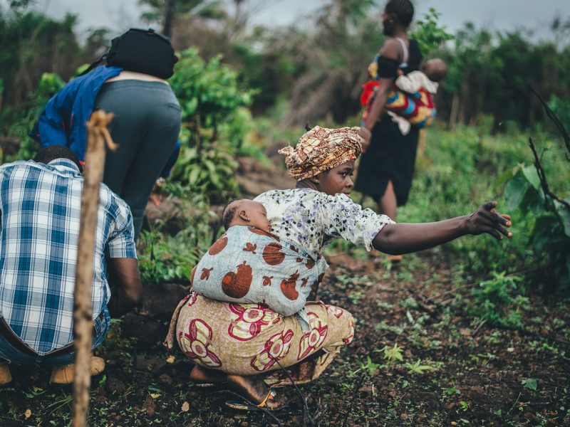 Photo by Annie Spratt woman carrying toddler at back while planting