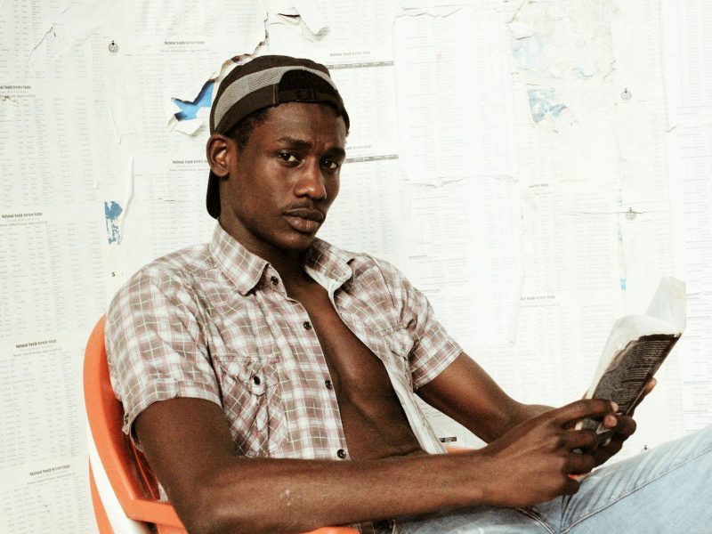 Photo by Muhammad-Taha Ibrahim man in white and red plaid button up shirt sitting on red plastic chair