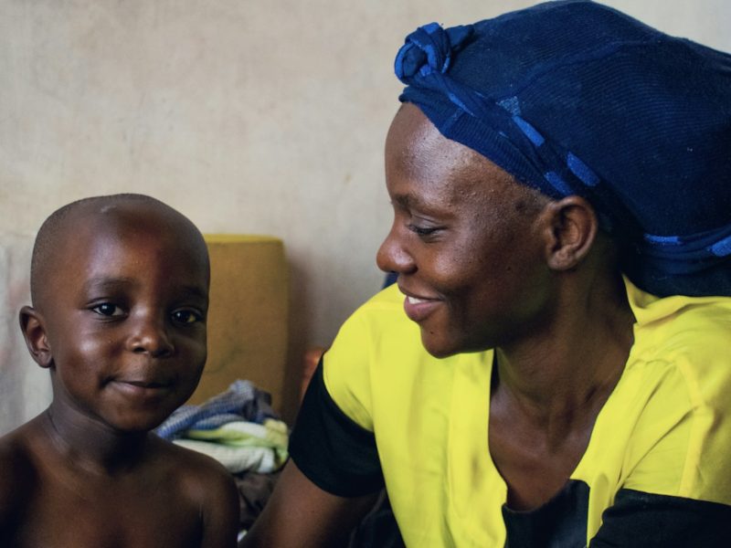 A woman sitting next to a child on a bed